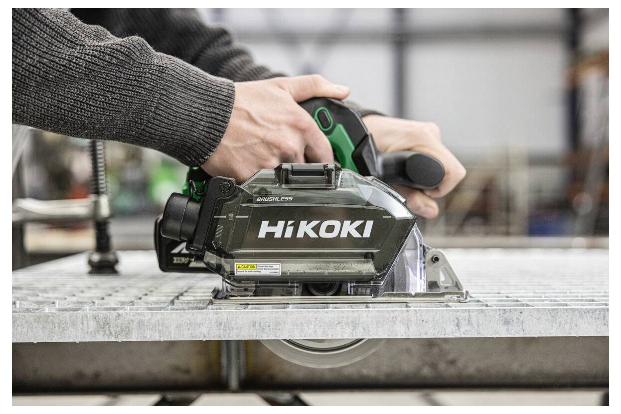 A person operates a HiKoki circular saw, cutting through metallic material on a workbench, illustrating its use in industrial settings.