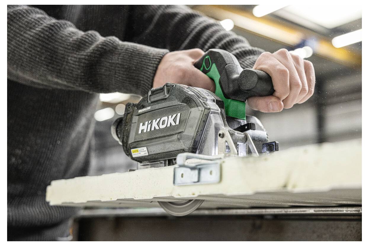 A person uses a power tool to cut through a piece of material. The tool is branded 'Hikoki'. The background shows an industrial setting.