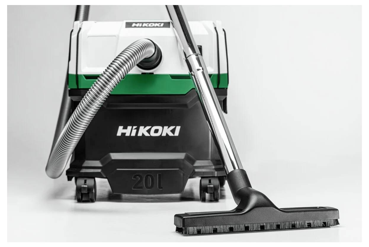A Hikoki vacuum cleaner with a green and white body, black hose, and attached cleaning nozzle, designed for industrial use.
