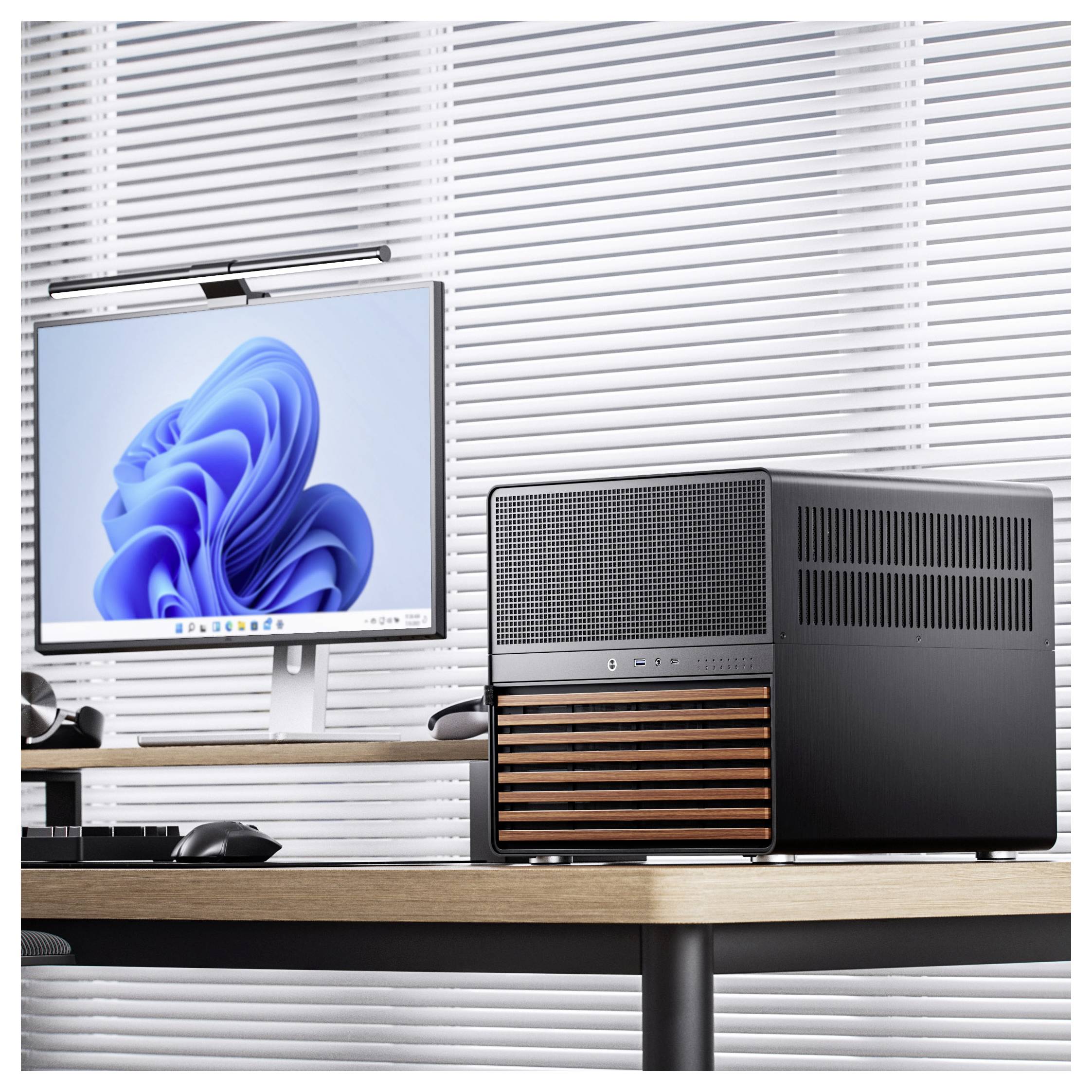 A modern computer setup on a wooden desk featuring a cube-shaped black PC case with wooden accents and a monitor displaying a blue abstract pattern.