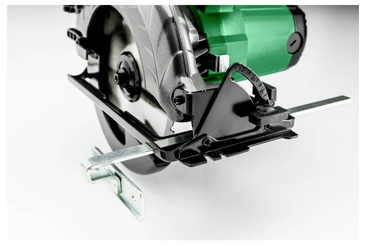 A close-up of a power circular saw with a silver blade and green motor casing, showcasing its metallic cutting guide and base plate.