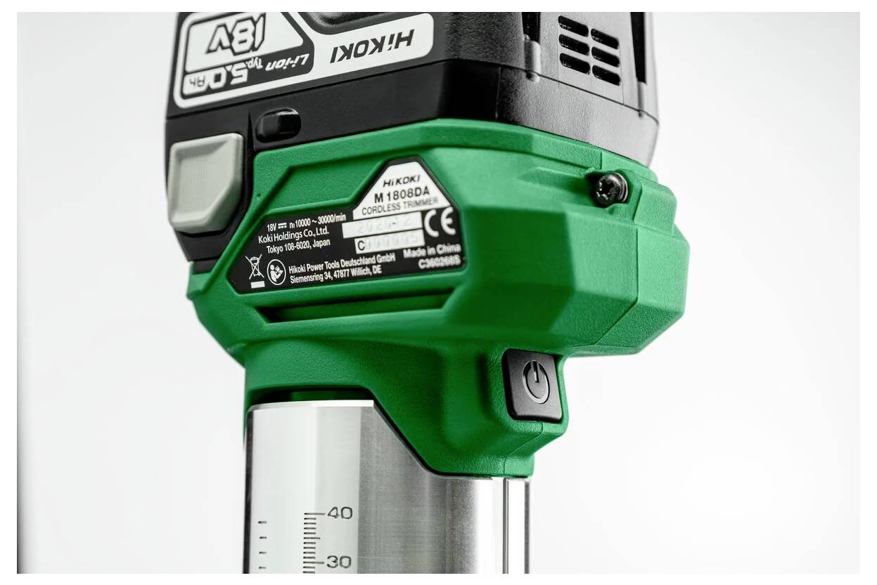 A green and black power tool with a measuring guide on its side. Visible buttons and labeling indicate model and manufacturing details.
