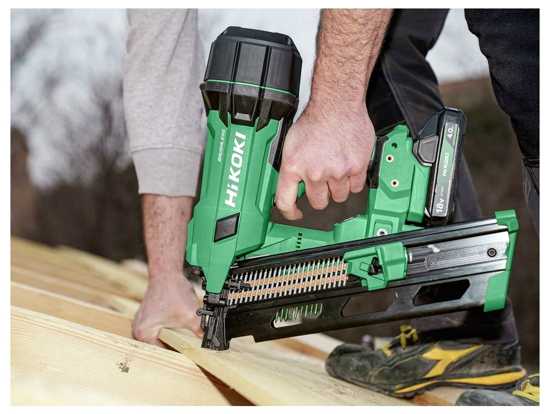 A person uses a green HiKOKI cordless nail gun to secure wooden planks, highlighting carpentry work in progress.