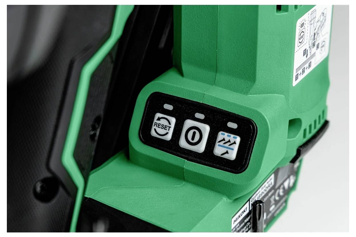 Close-up of green power tool showing three buttons: 'Reset', power button, and water splash symbol. Black casing with labels and specifications.