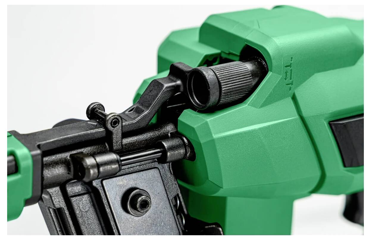Close-up of a green and black mechanical tool, featuring a grip handle and adjustable component, possibly a nail gun or power tool.