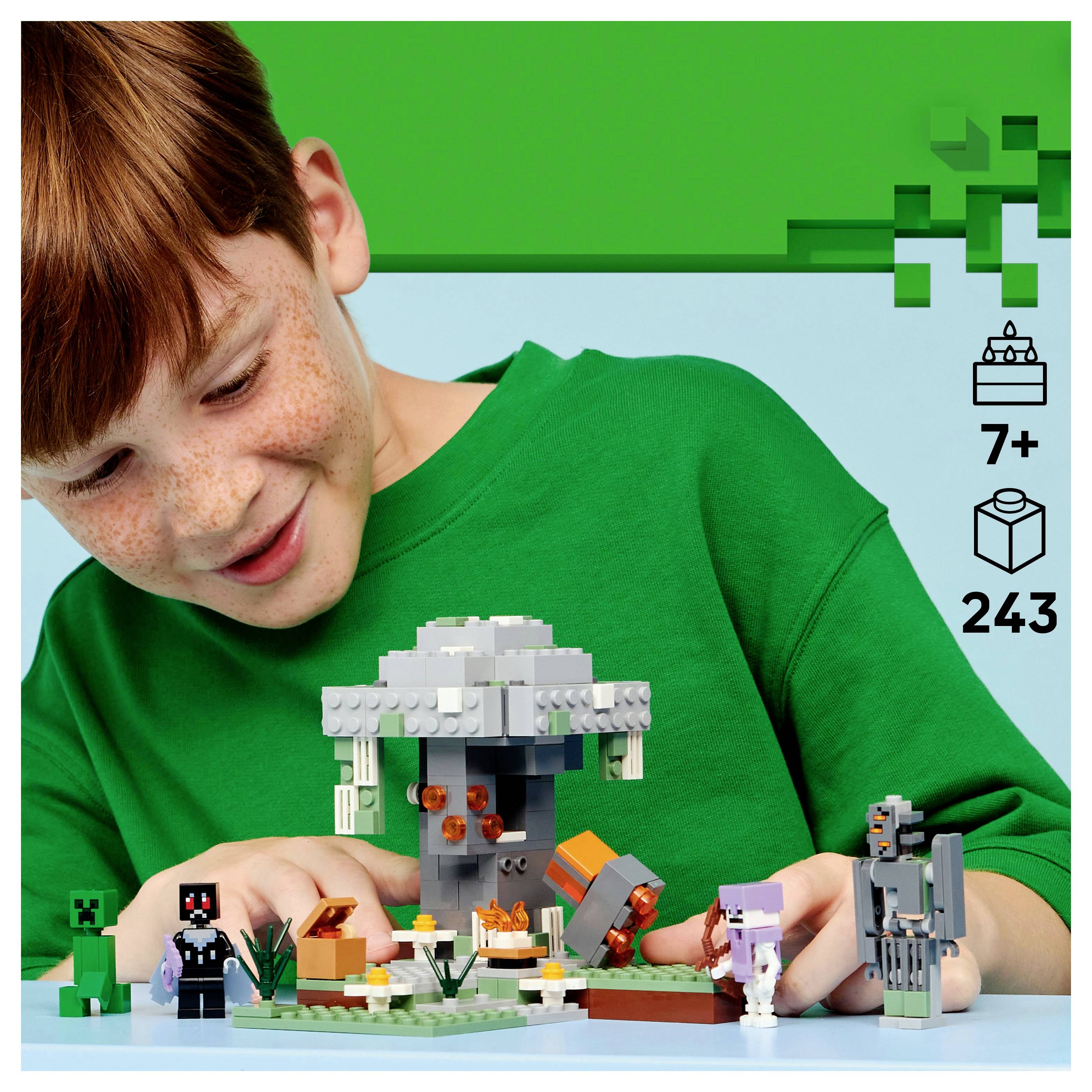 A child in a green shirt builds with block toys, featuring a gray structure and small character figures. Icons suggest it's for ages 7+ with 243 pieces.