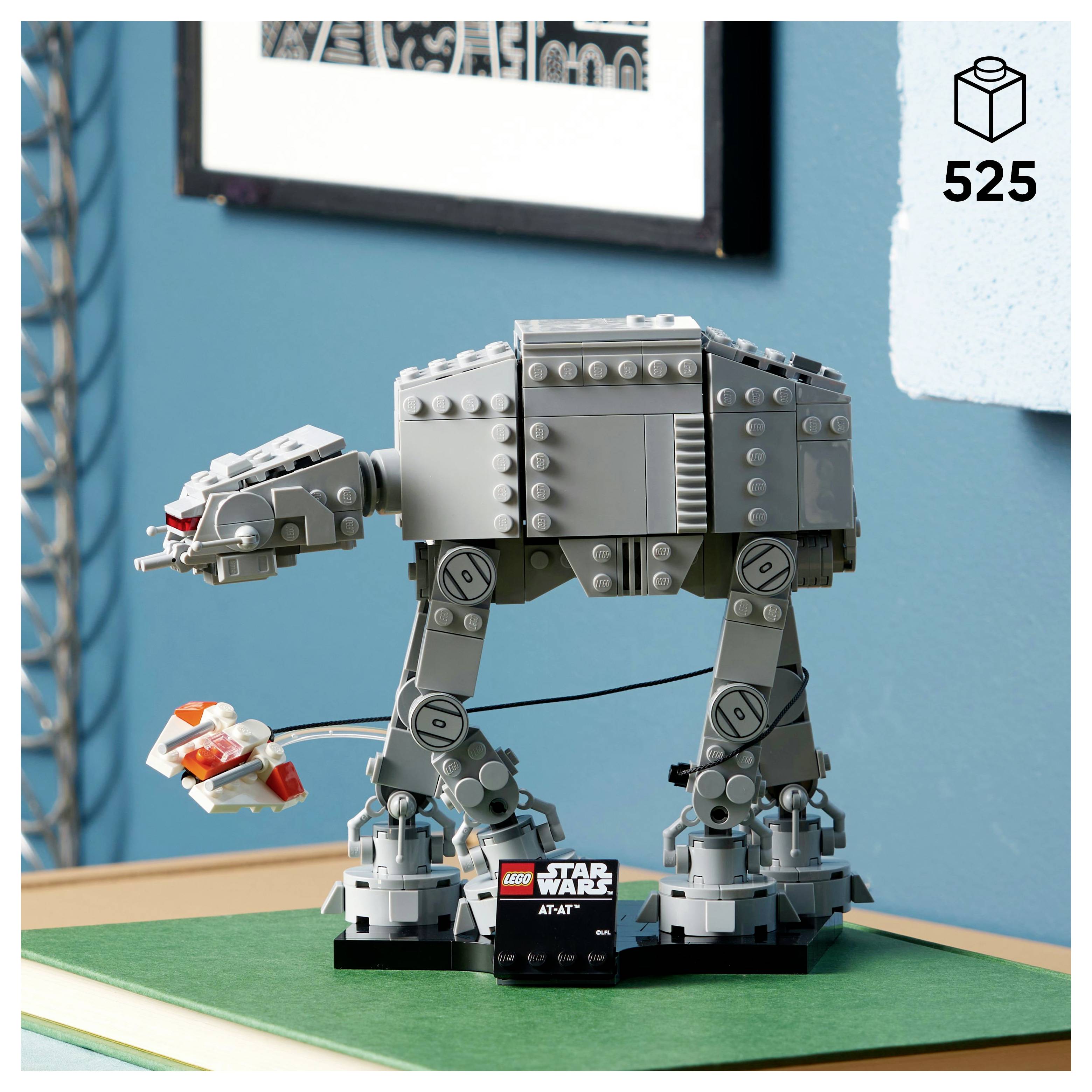 LEGO model of an AT-AT from 'Star Wars' on a green surface, with a smaller LEGO figure beside it. Box indicates set number 525.