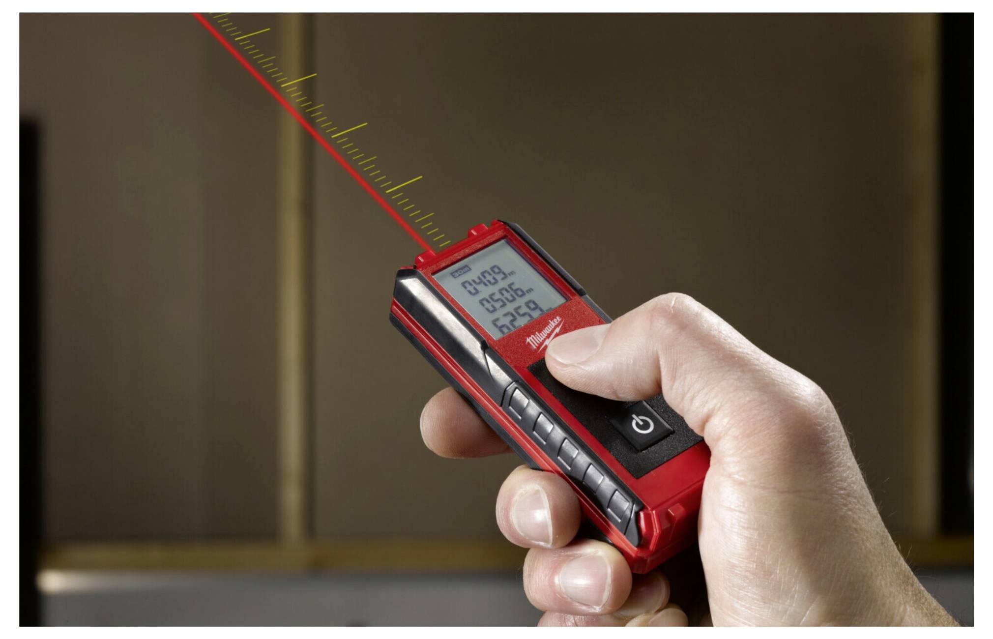 A hand holds a digital laser distance measurer, displaying '25.36 m' on the screen, pointed to measure a vertical surface.