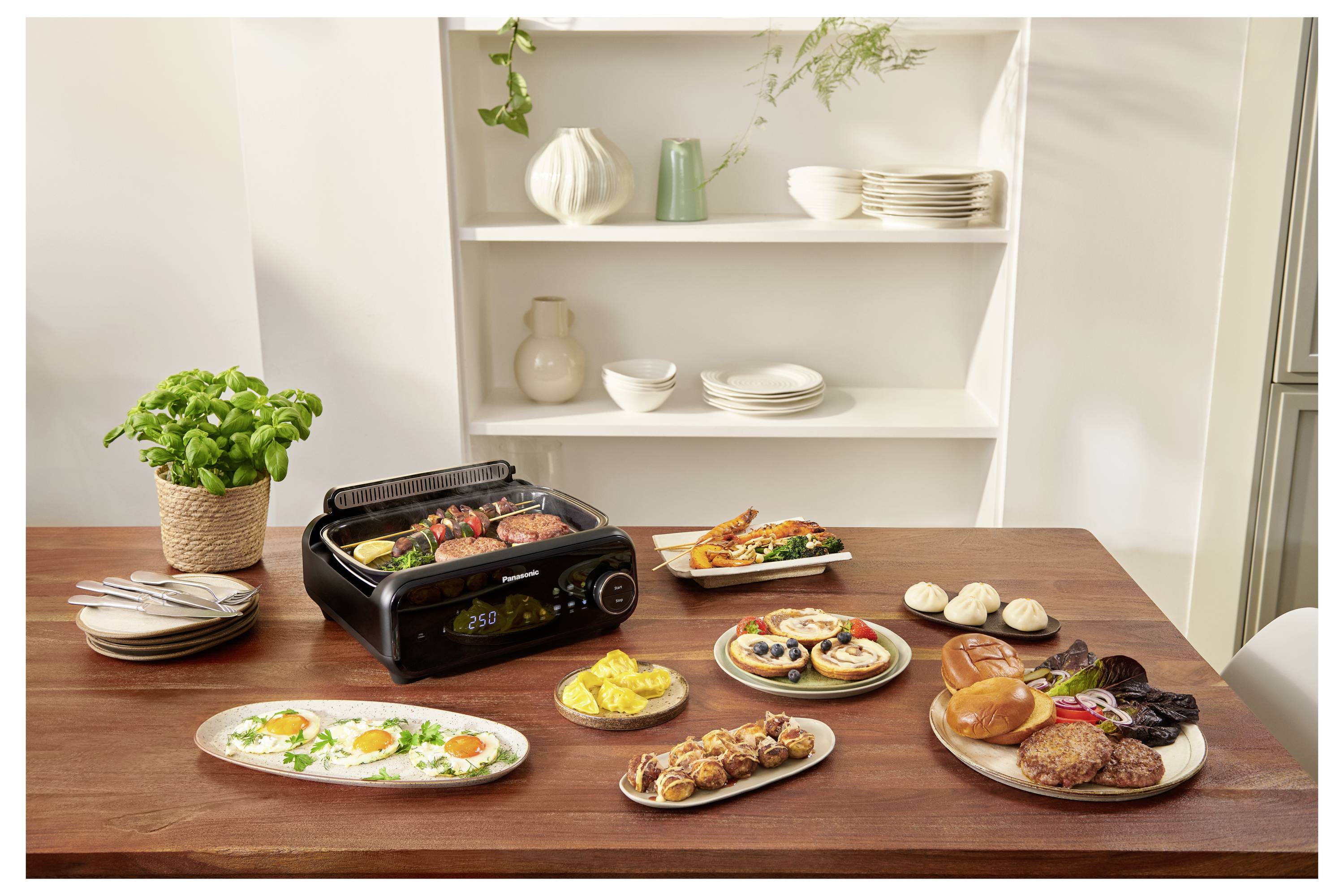 A variety of cooked dishes displayed on a table with a grill. In the background, shelves with white plates, bowls, and decorative vases.