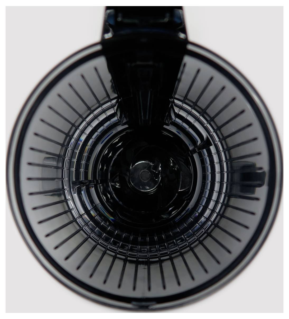 Top view of an empty blender jug with blades visible at the bottom, surrounded by a clear plastic container.