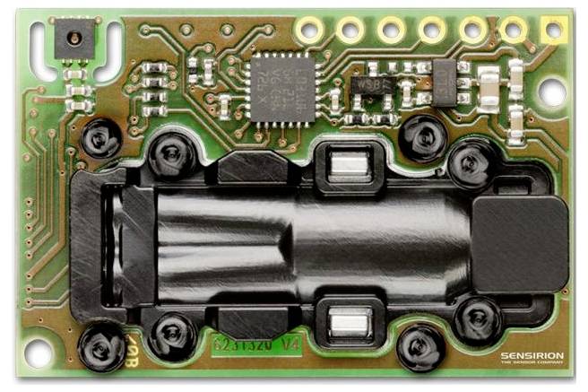 Electronic circuit board with a central black component, several small chips, and multiple connectors. The word 'SENSIRION' is visible.