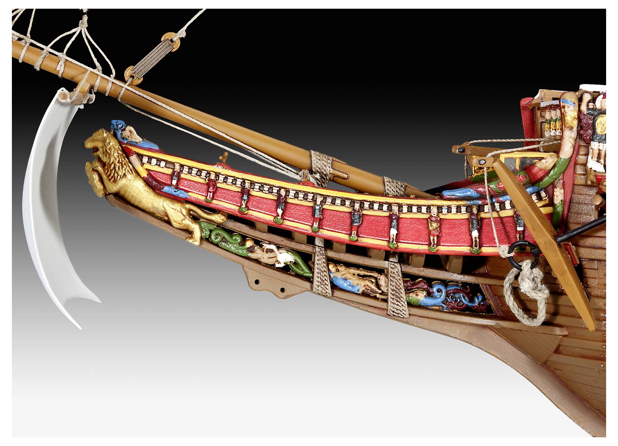 A detailed model ship prow with a golden lion figurehead and ornate red and gold detailing against a neutral background.