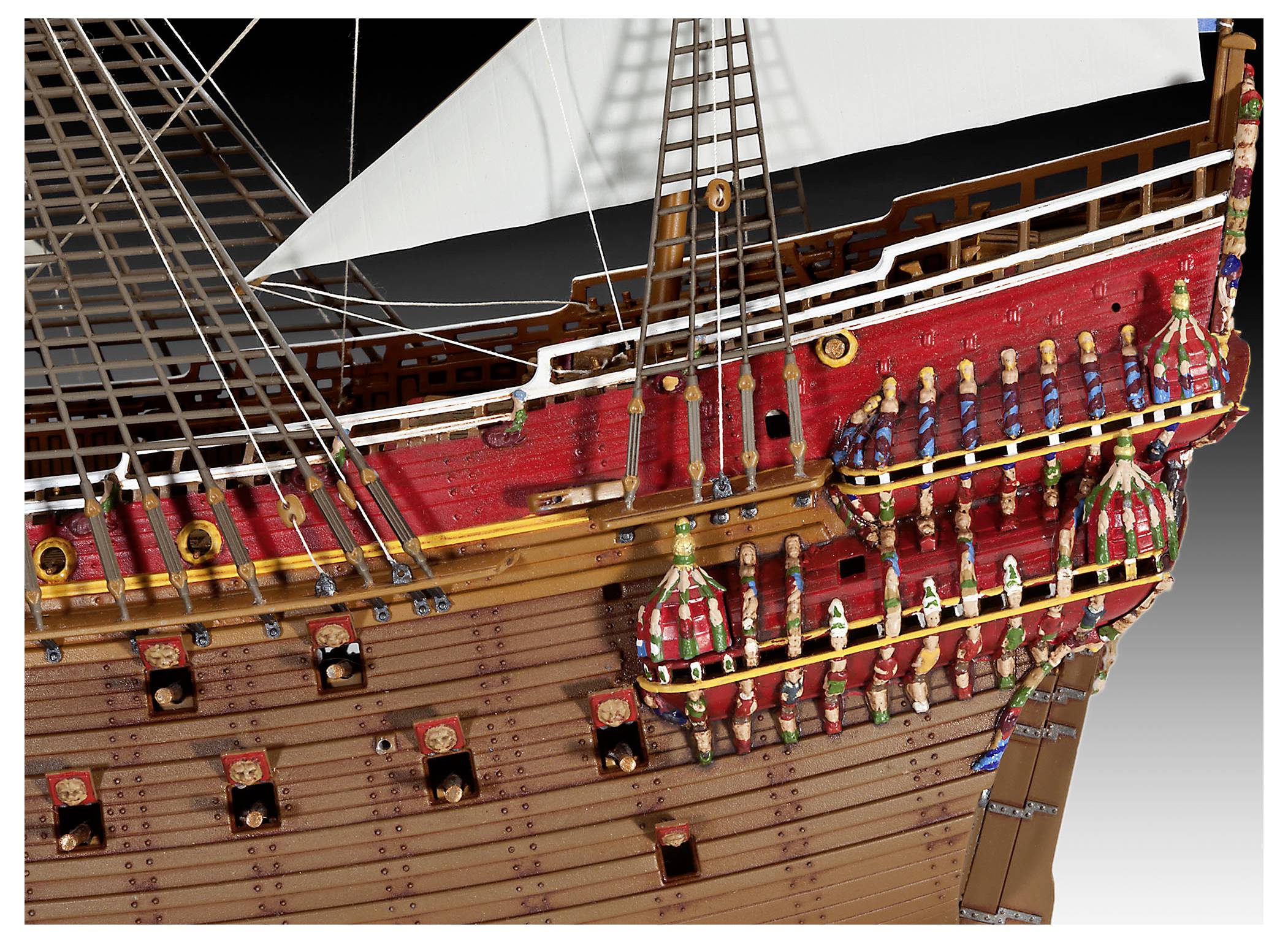 Model of a historic sailing ship, showing detailed rigging, red-painted upper deck with ornate decorations, and numerous cannon ports.