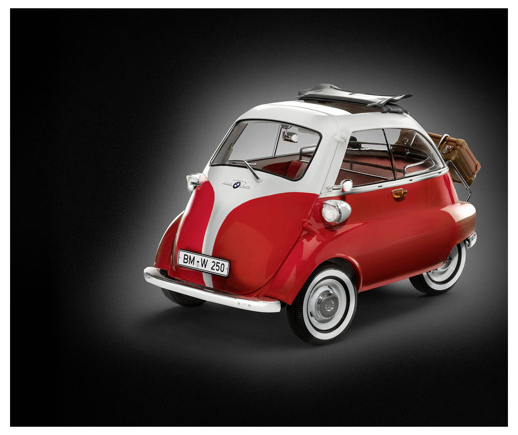 A small red and white vintage car with two wheels at the front and a luggage rack at the back.