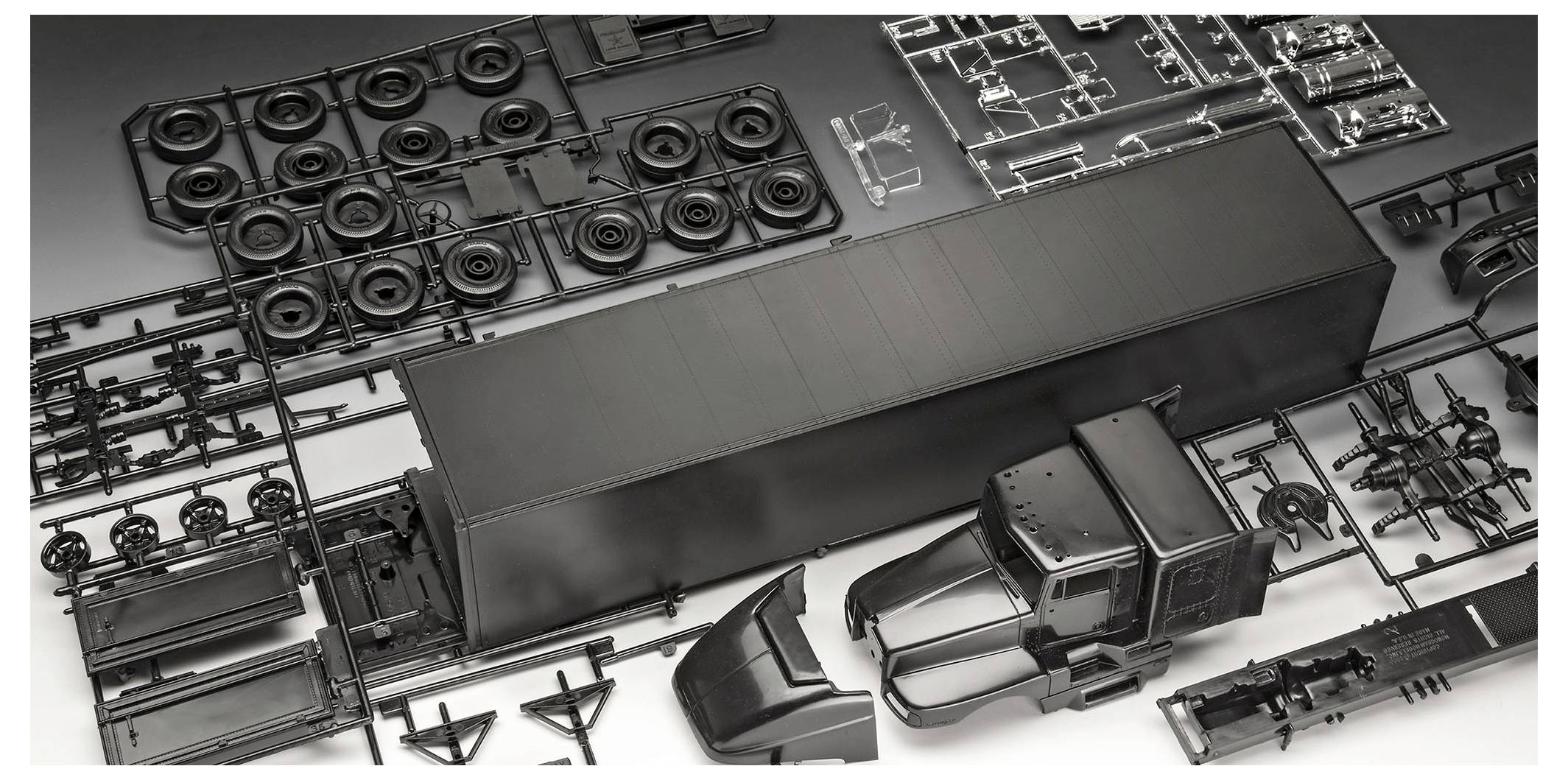 Model kit parts laid out in sprues, including truck body, tires, and cab components, ready for assembly.