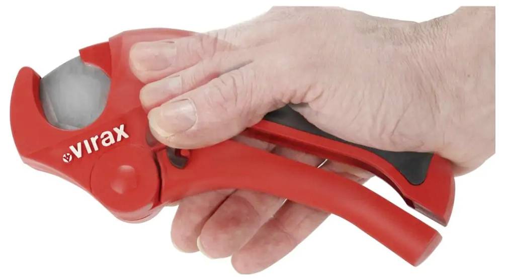 Hand using a red Virax pipe cutter to cut a grey pipe