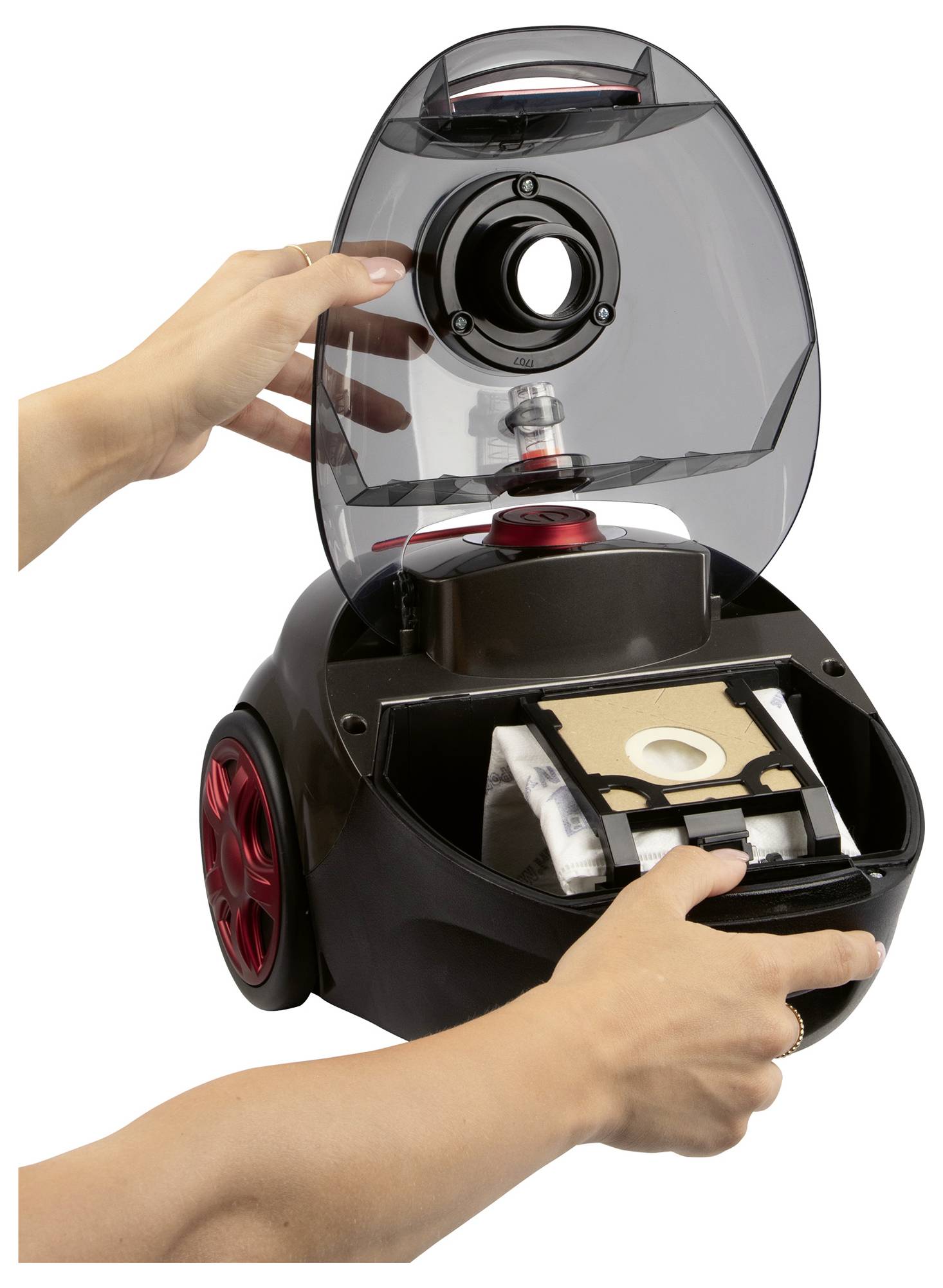 A person demonstrating how to change a vacuum cleaner bag by opening the top compartment and removing the bag from the inner section.