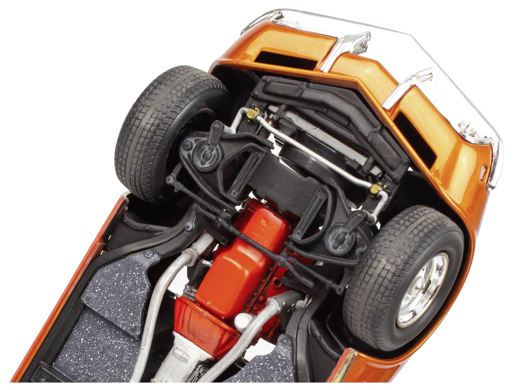 Underside view of an orange car model, showing detailed suspension, exhaust system, and engine components. The perspective focuses on the front axle.