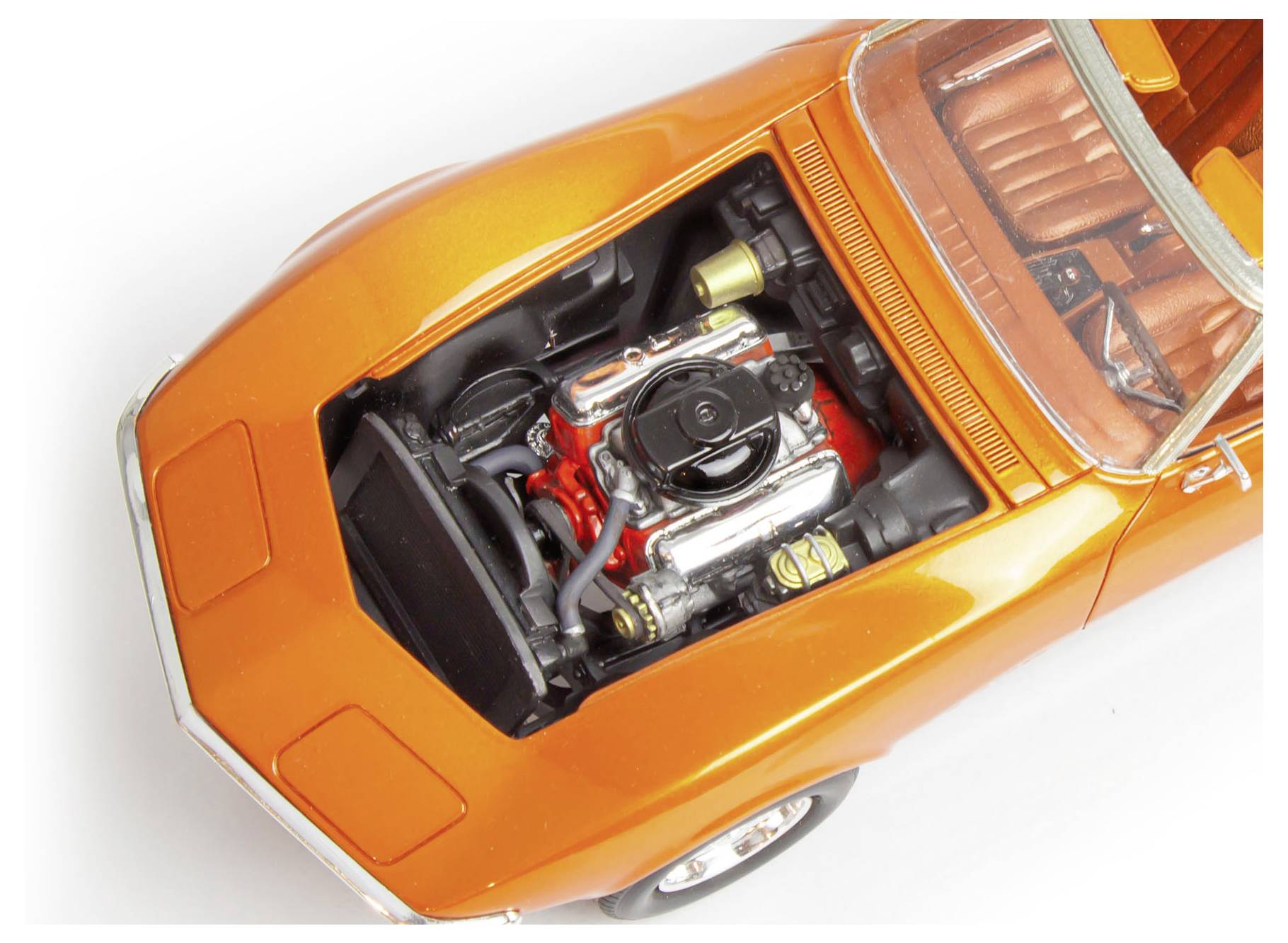 An orange classic car model with its hood open, revealing a detailed engine. The interior is visible, showing part of the seating.