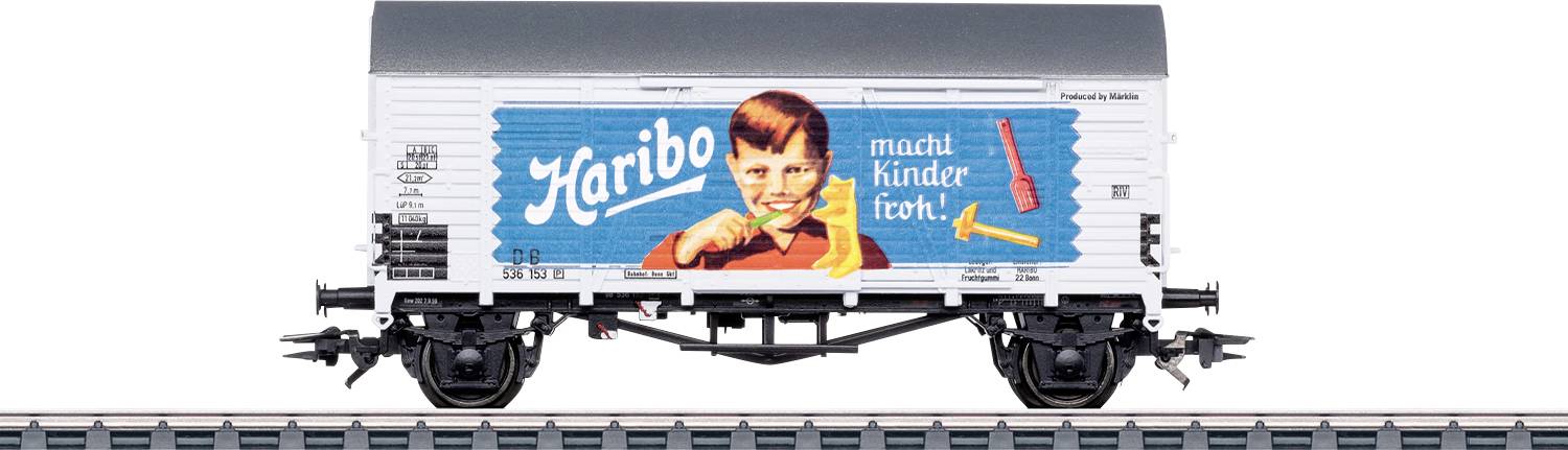 A model train car with a vintage 'Haribo' advertisement. The ad features a smiling child holding a gummy bear, with German text.