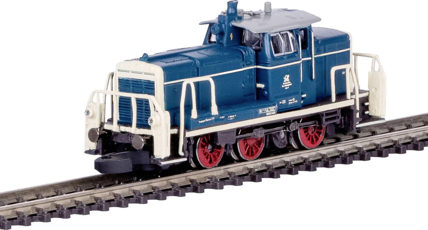 A small blue and white model train engine with red wheels is displayed on tracks. The train features detailed railings and a smokestack.