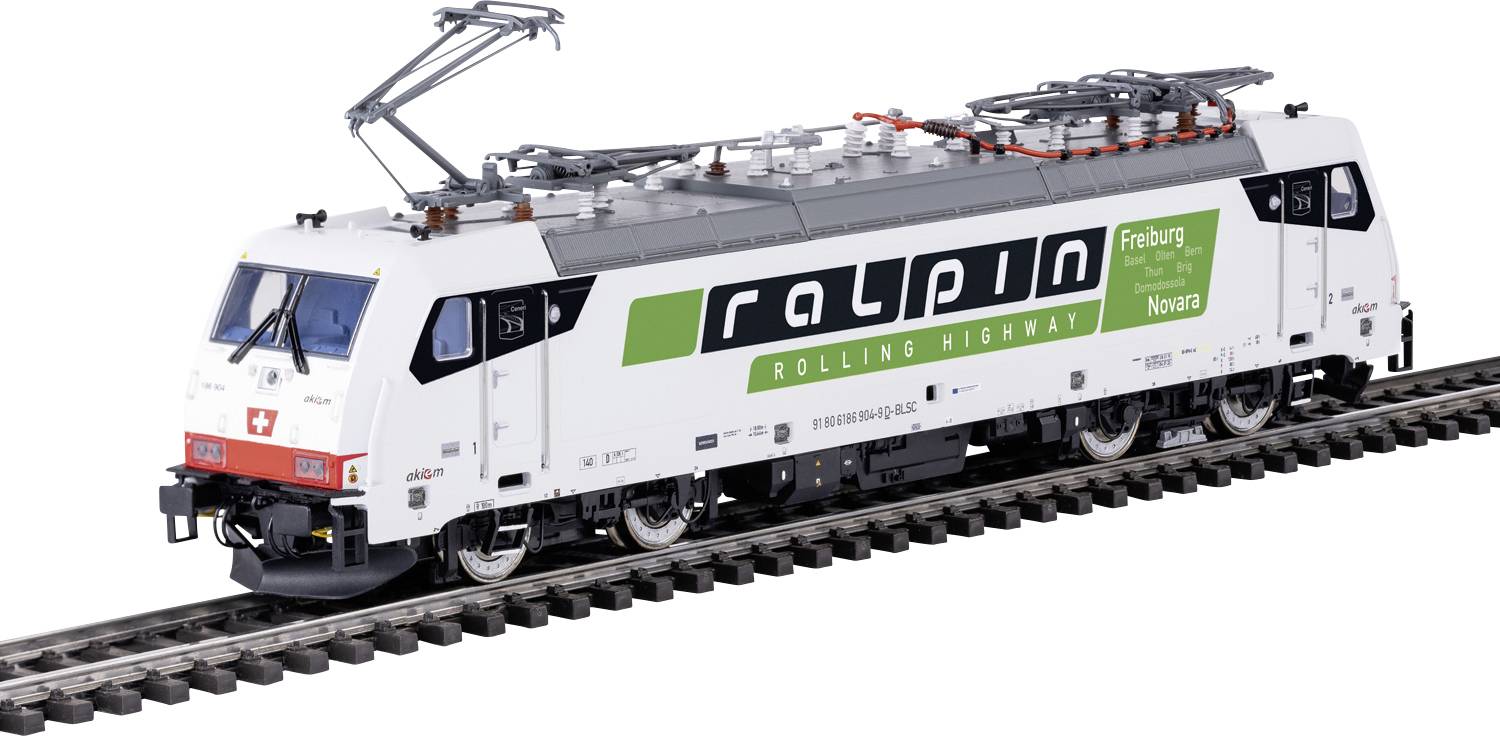 A white locomotive on train tracks with the logo 'ralpin' and the text 'Rolling Highway'. It's equipped with a pantograph on top.