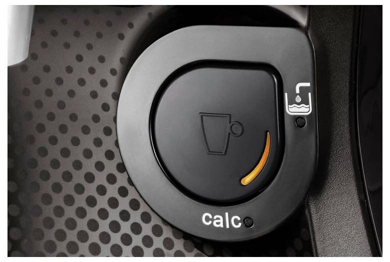 Close-up of a coffee machine's control knob, showing an orange light indicator and 'calc' written below, indicating descaling is needed.