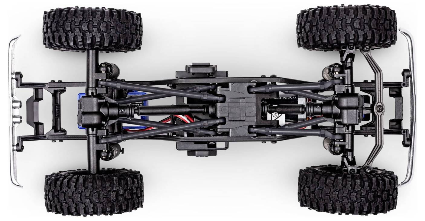 A close-up, top-down view of an RC truck chassis showing suspension, wheels, and wiring, highlighting its mechanical layout and design.