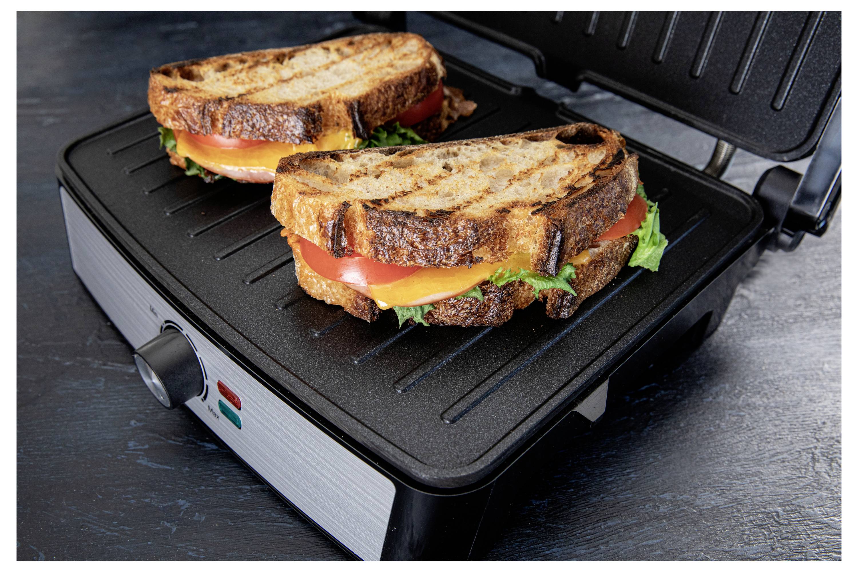Grilled cheese and tomato sandwiches with lettuce on a sandwich press, browning to perfection.