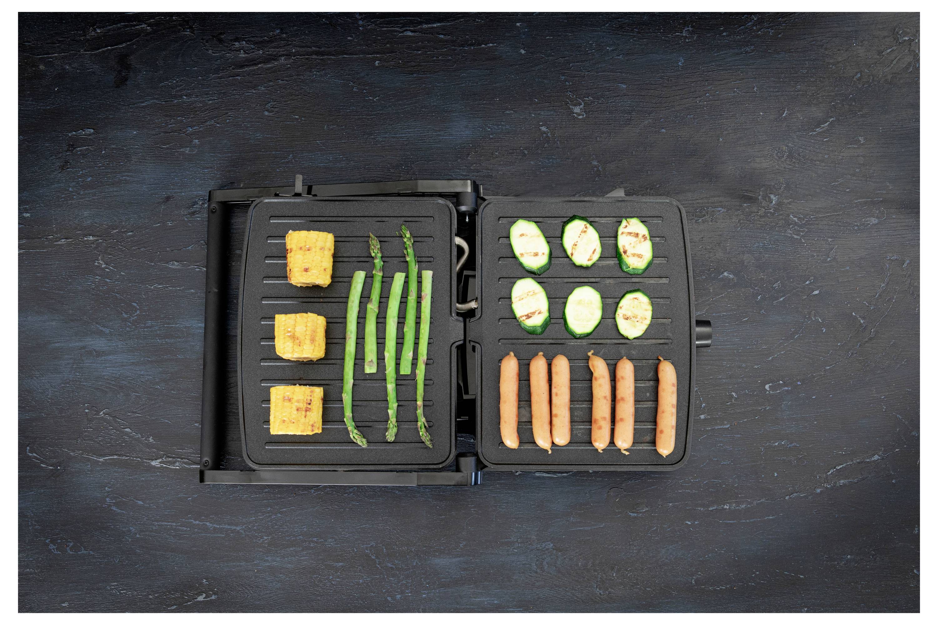 Electric grill with tofu cubes, asparagus, zucchini slices, and sausages arranged neatly on the grilling surface.