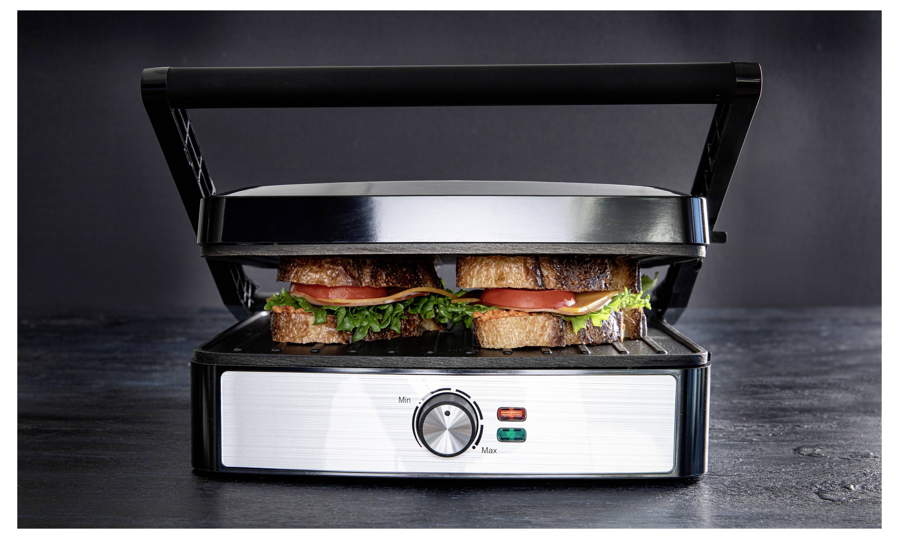 A sandwich press with two grilled sandwiches inside, filled with lettuce, tomato, and cheese. The dial is set on medium heat.