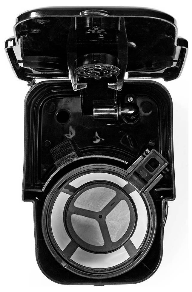 Top view of an open coffee machine filter compartment, showing a circular mesh filter inside a black coffee maker.
