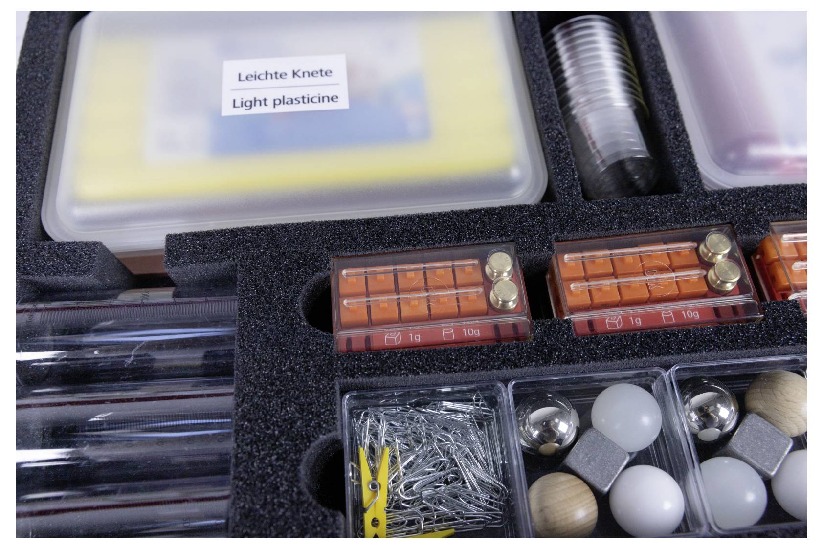 Case with assorted educational materials labeled 'Light plasticine', featuring plasticine, weights, pegs, nails, and balls.