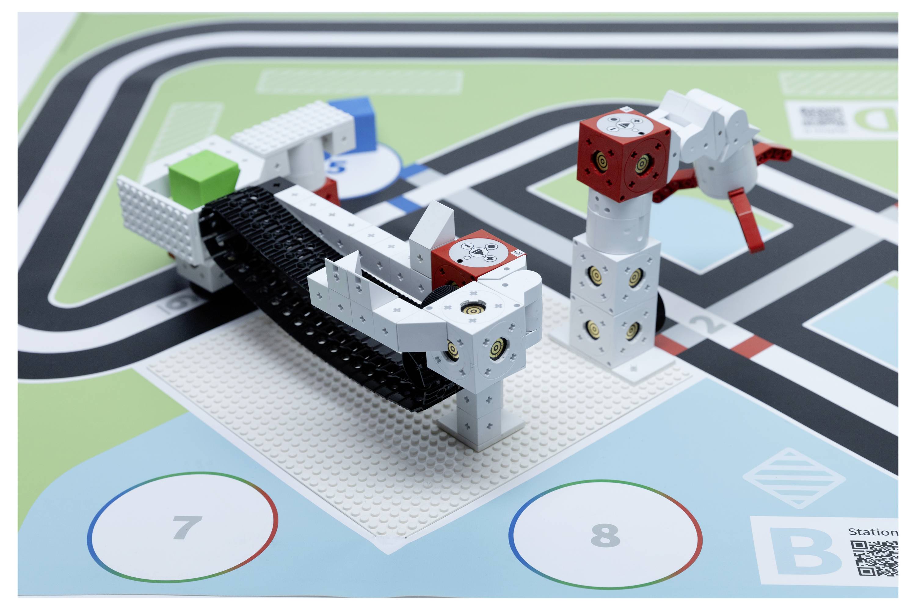 Robotic assembly on a printed circuit represents a vehicle and an animal figure, placed on a track with marked lanes and numbered circles.