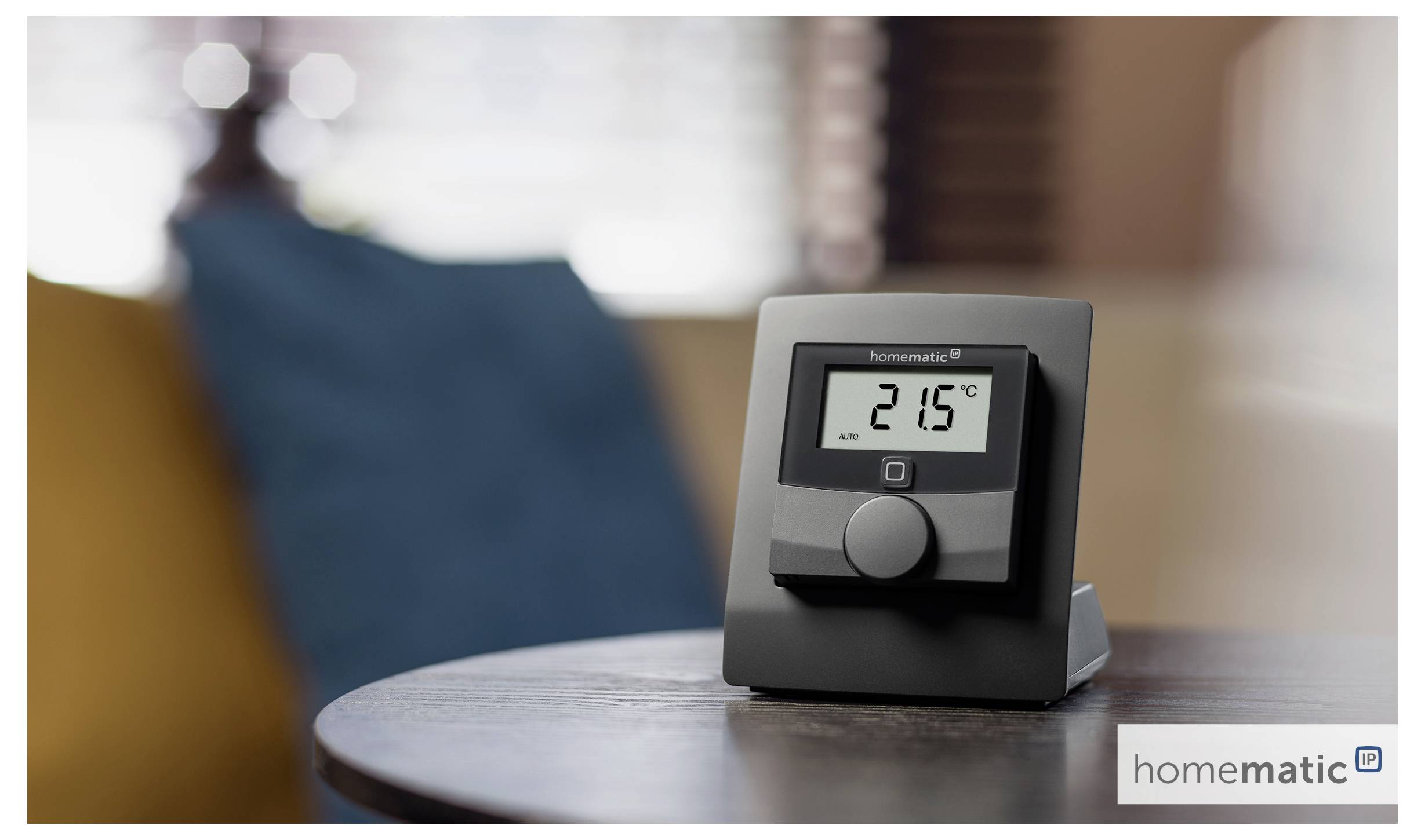 A digital thermostat on a table displays '21.5°C'. The background includes blurred furniture, suggesting a home setting.