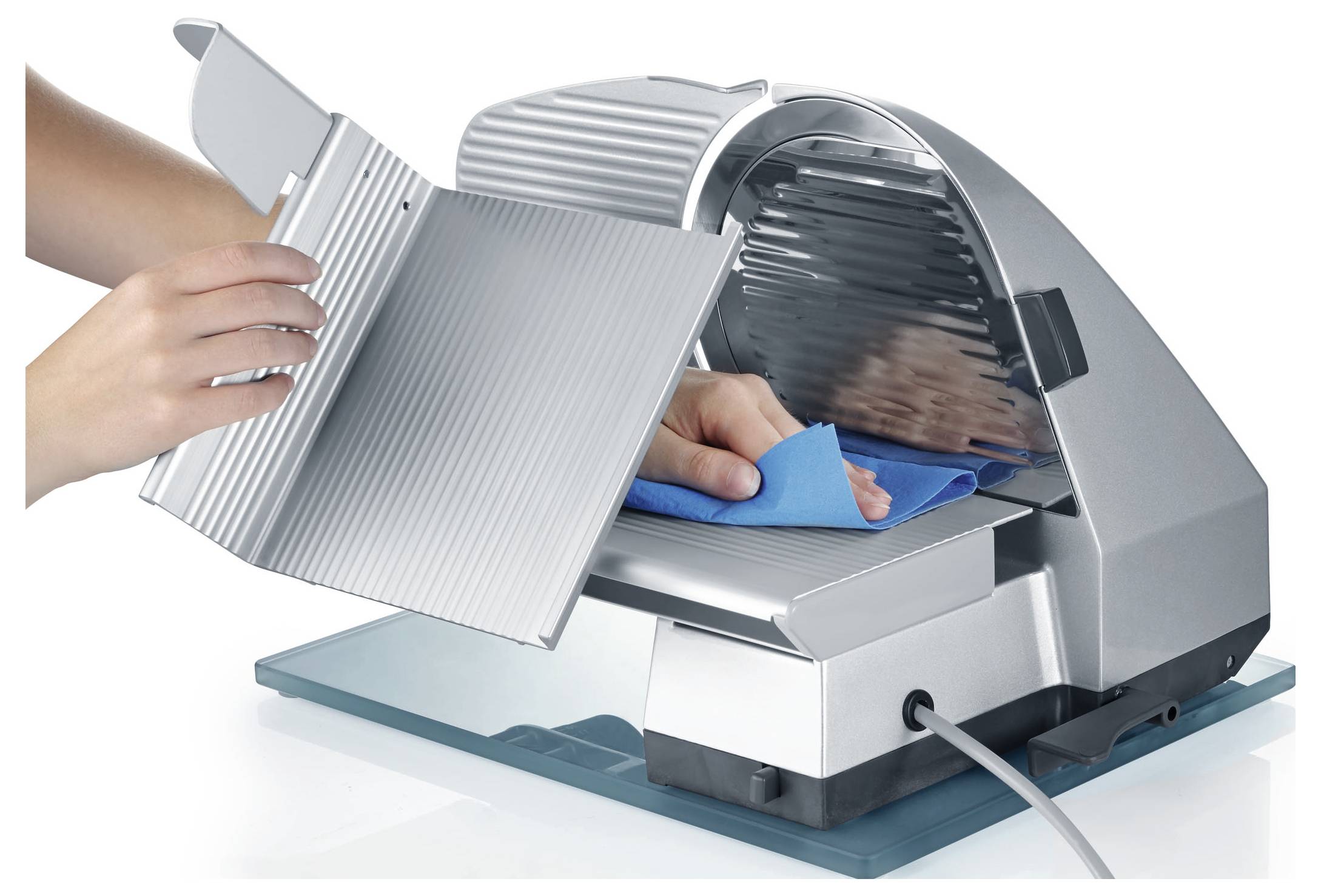 Hands cleaning a metal slicer with a blue cloth, illustrating proper maintenance of kitchen equipment.