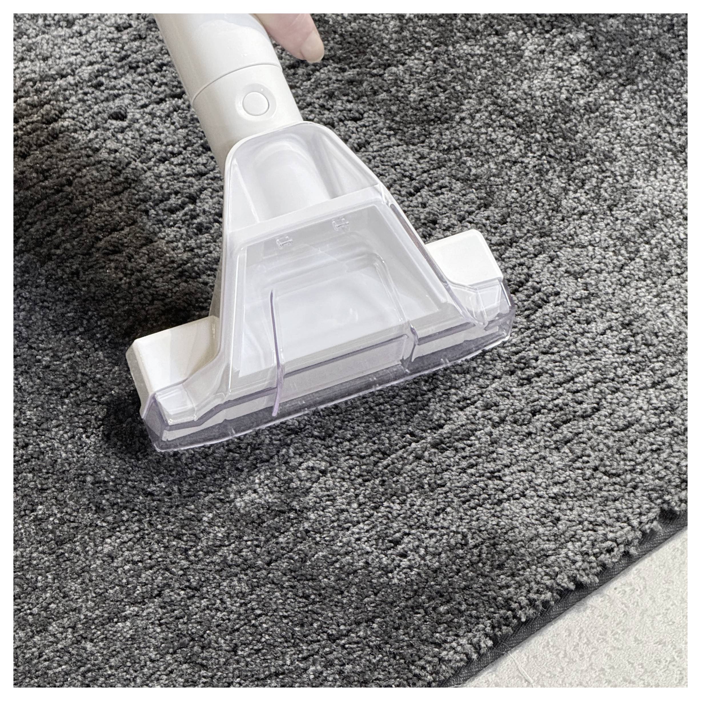A vacuum cleaner nozzle is being used on a gray carpet, showing the cleaning activity.