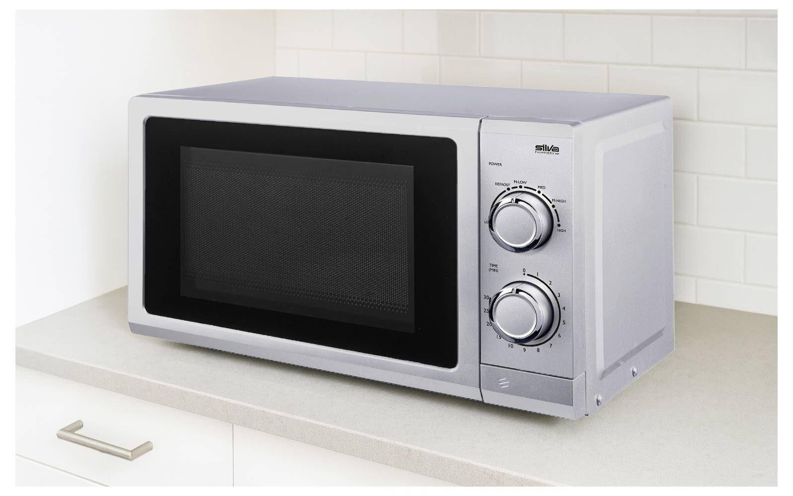 Stainless steel microwave oven on kitchen counter with two control knobs and digital display, set against a tiled backsplash.