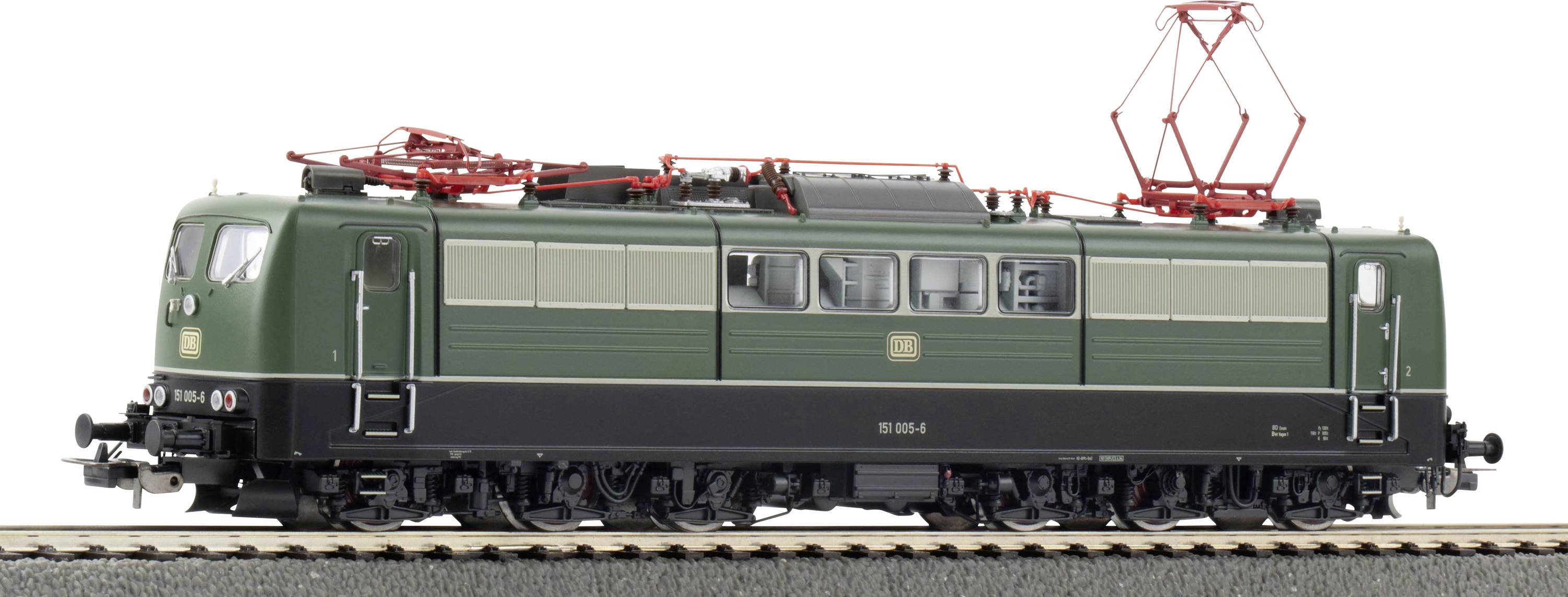 Green model train locomotive on tracks with red wiring and black base, featuring windows along the side and red overhead connectors.