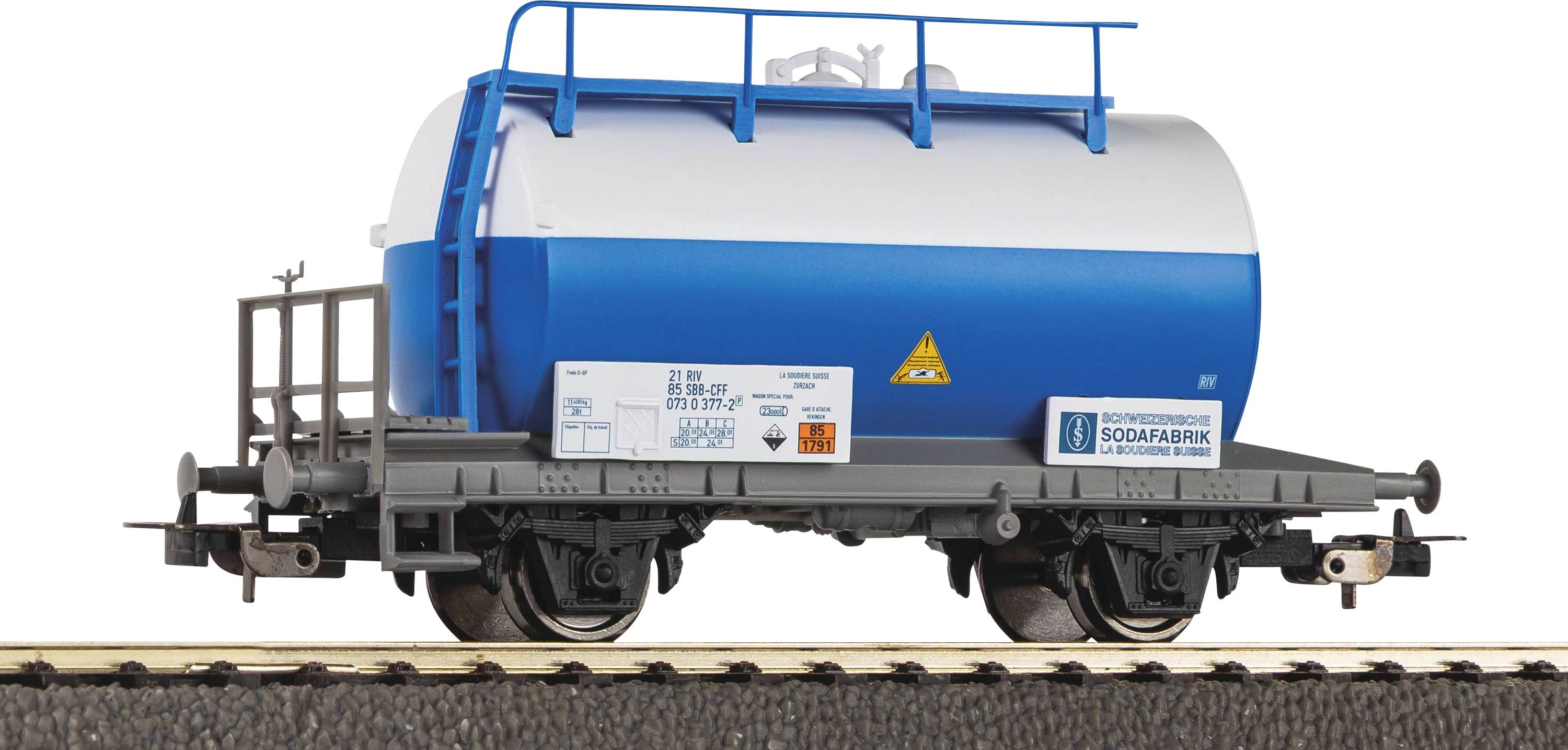 A model railcar features a blue and white cylindrical tanker, marked with safety labels, resting on a section of train track.