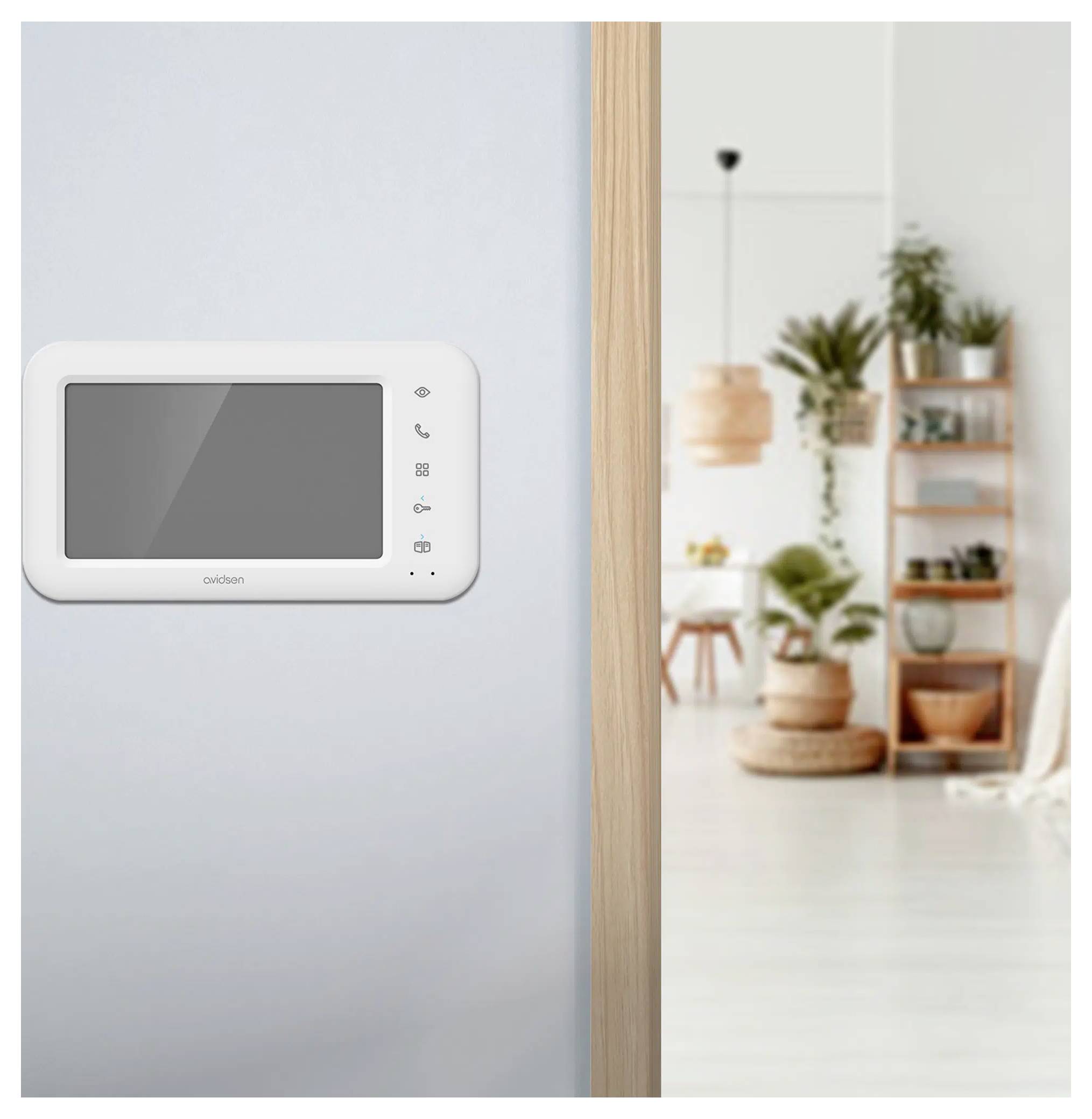 A home intercom system mounted on a wall in a modern living room with plants and shelves in the background.