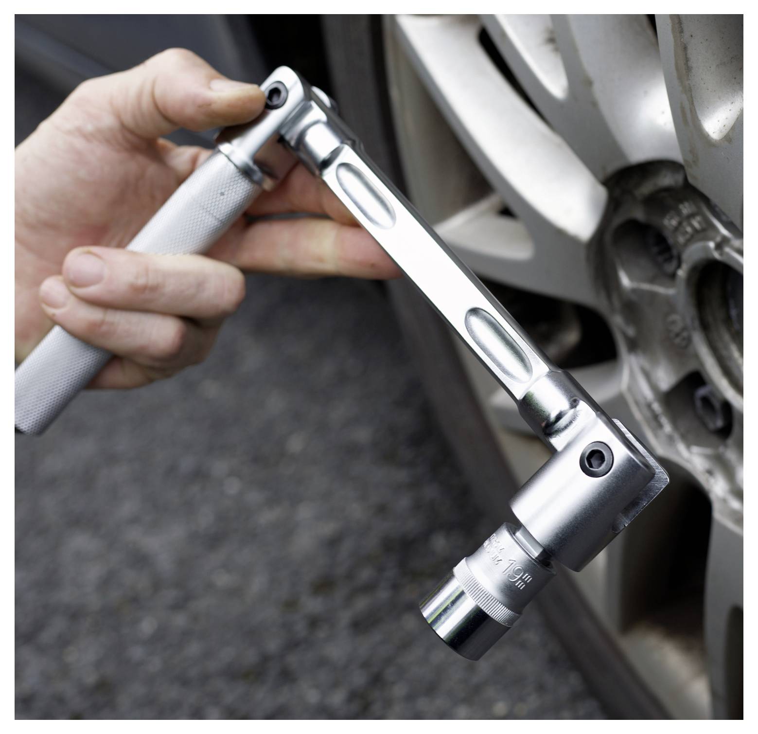 A hand using a torque wrench to tighten a lug nut on a car wheel, demonstrating proper tool use for vehicle maintenance.