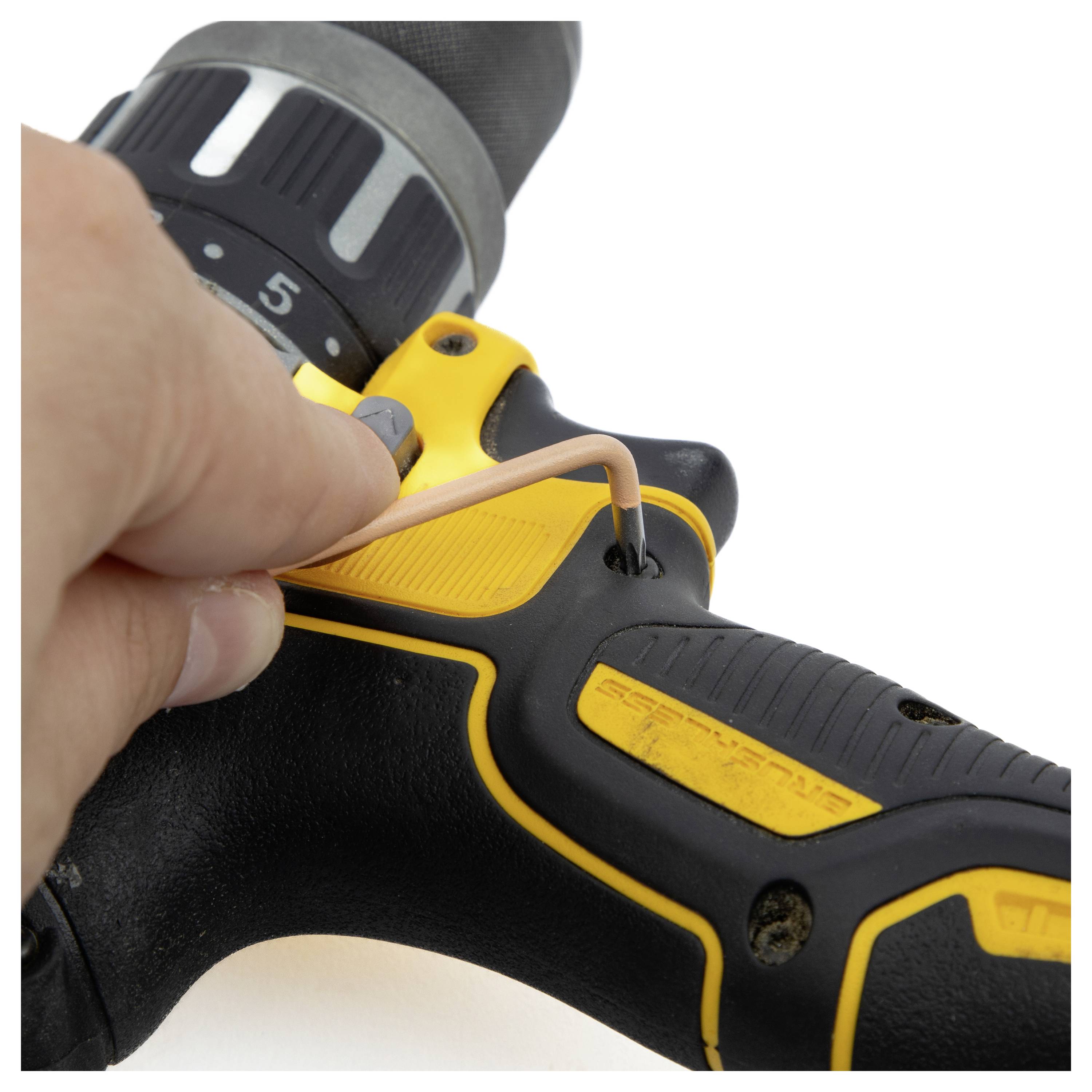 A hand using a hex key to adjust a yellow and black power drill, focusing on the tightening mechanism with visible numerical settings.