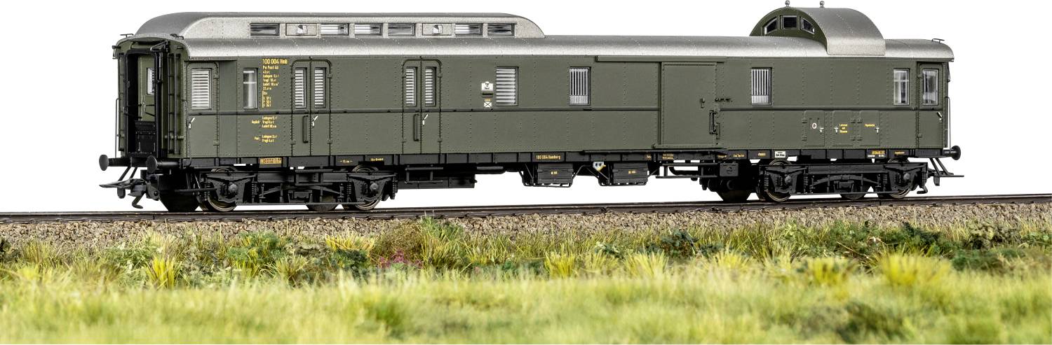 A model train car in green with detailed markings sits on a rail track, surrounded by grass, showcasing fine craftsmanship.