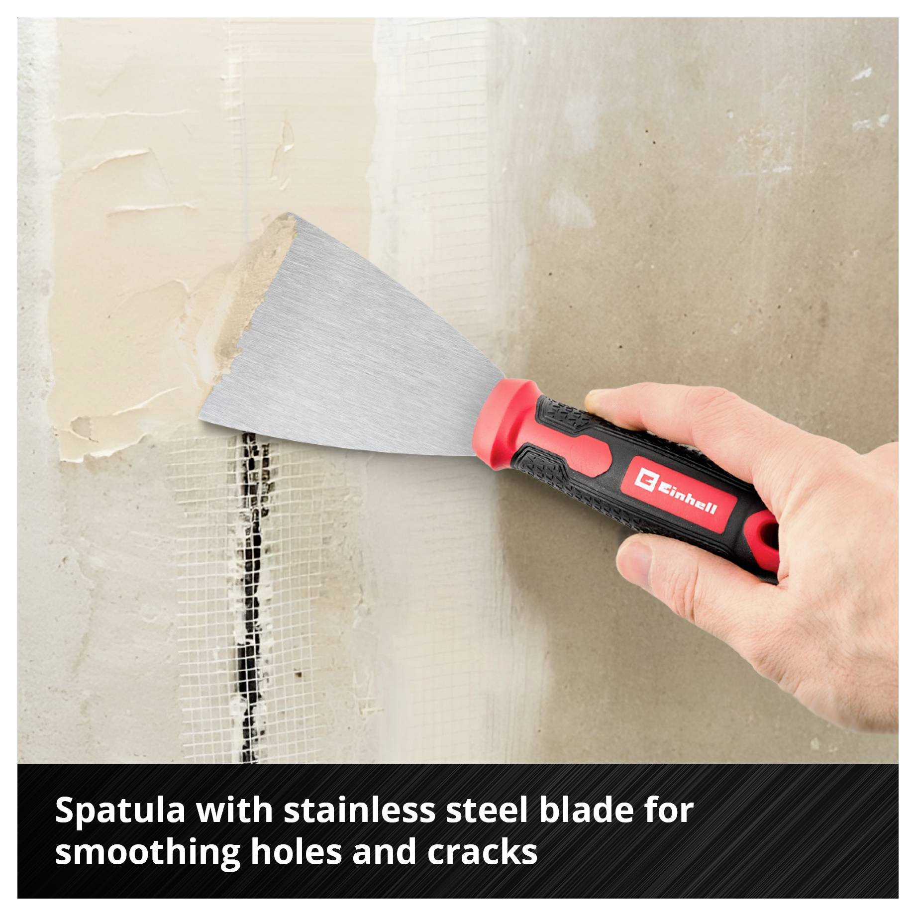Hand holds putty knife with stainless steel blade, smoothing cracks in the wall.