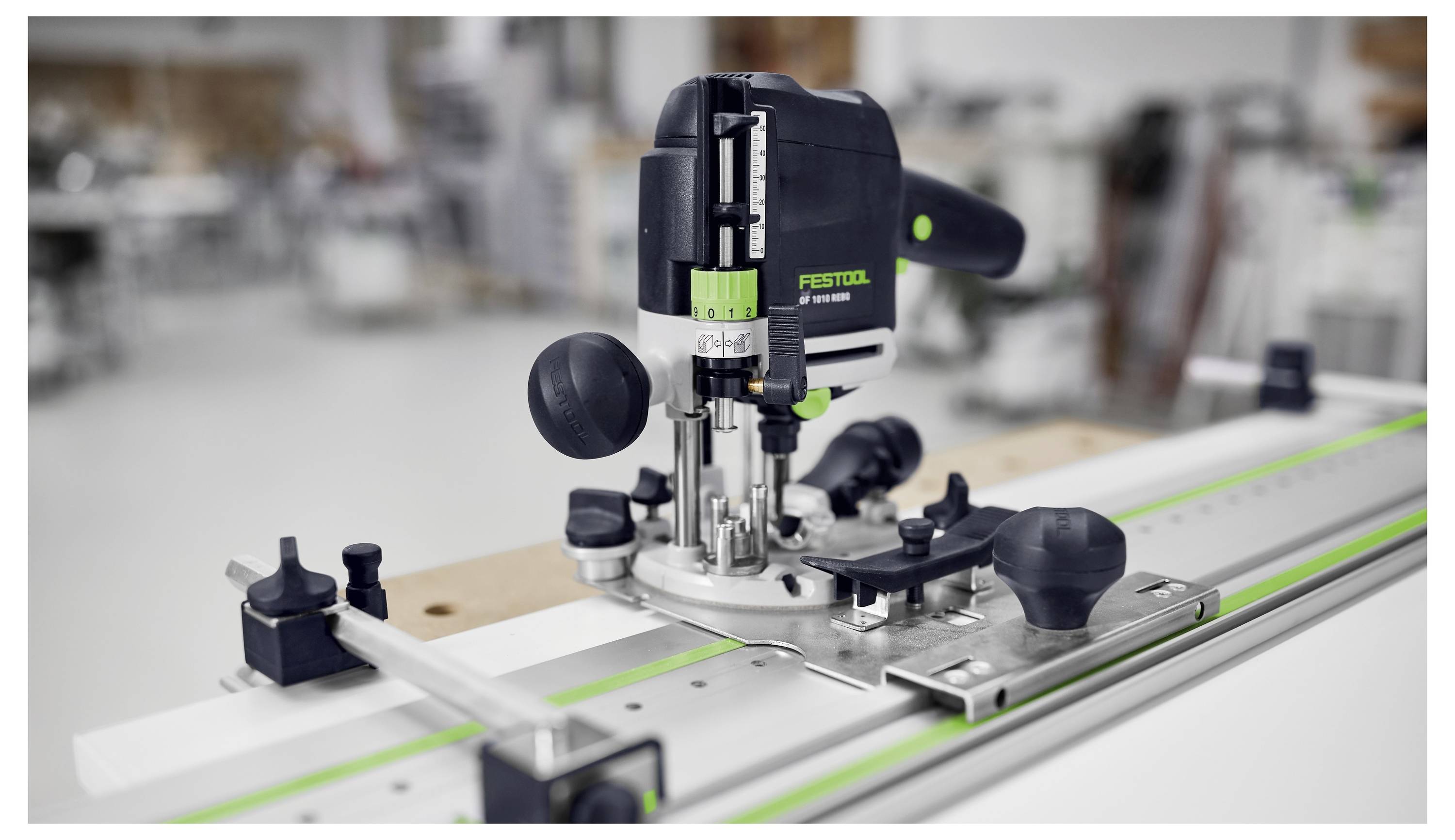 A power tool for routing wood is placed on a guide rail in a workshop setting, showcasing precision and functionality in woodwork tasks.