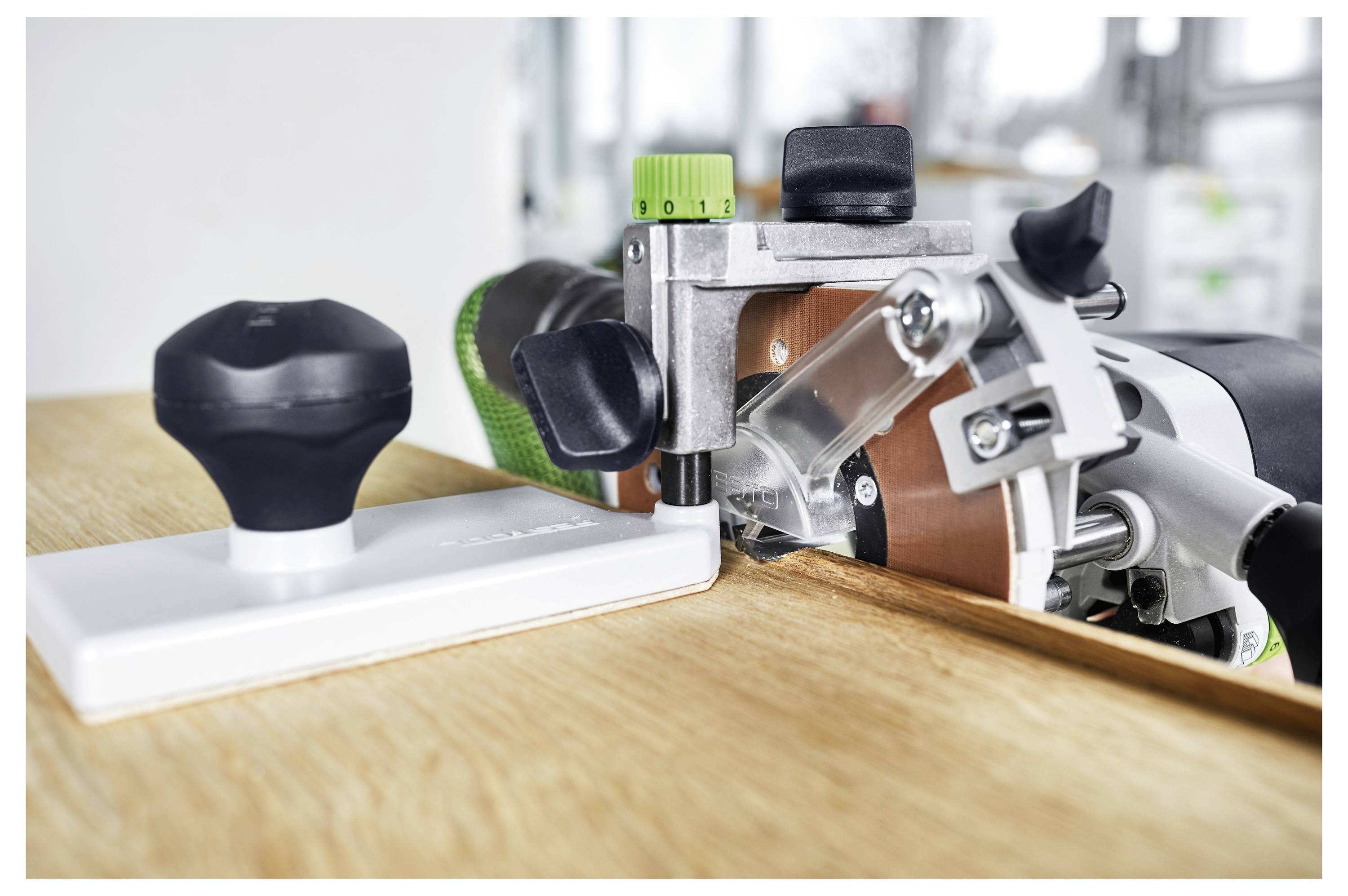 A woodworking router with an edge guide on a wooden surface, designed to create precise cuts and grooves at specific angles.
