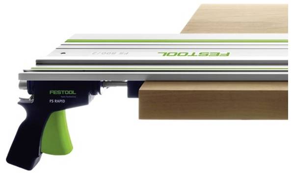 A precision cutting tool from Festool with a green handle clamps onto a wooden board, showcasing its use in carpentry for straight cuts.