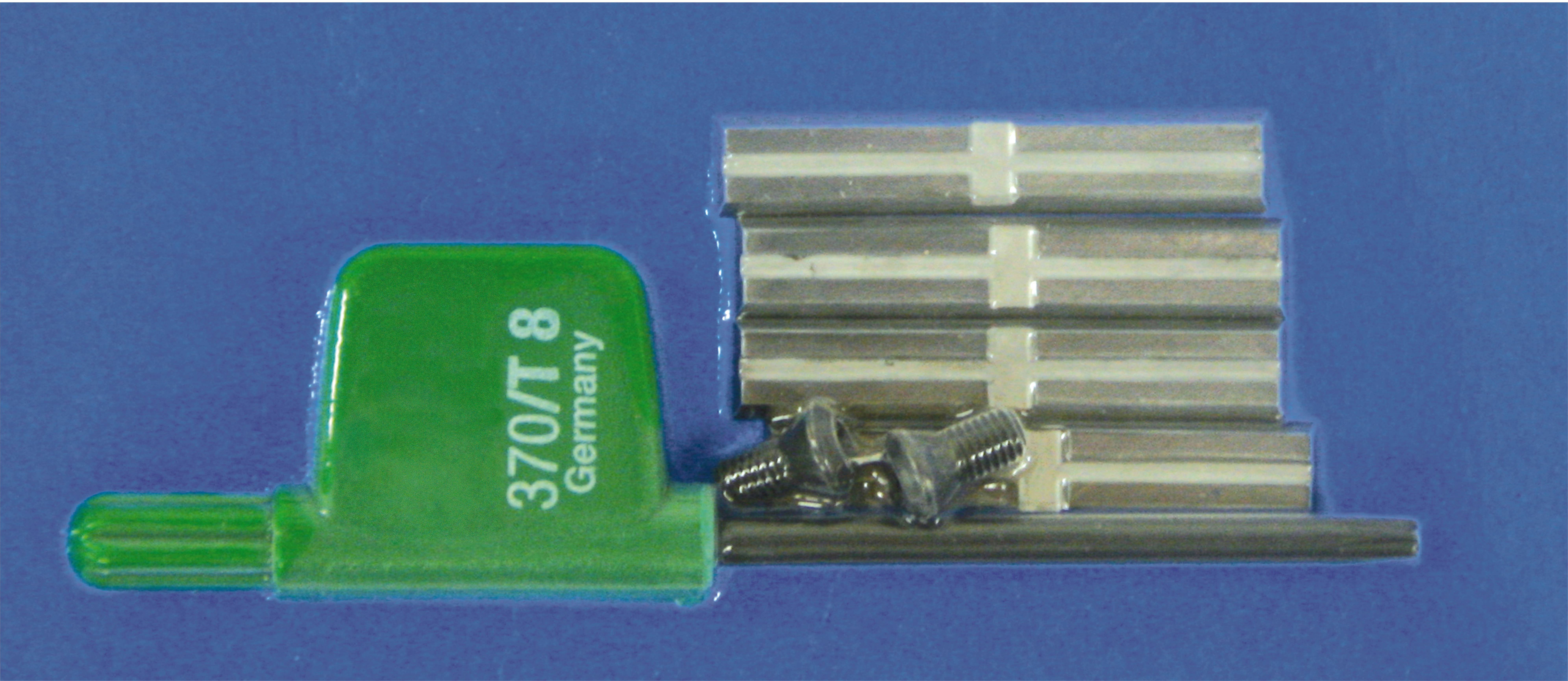 'A dental tool kit with a green tool marked '370/Г 8 Germany', metal strips, and small screws on a blue background.'