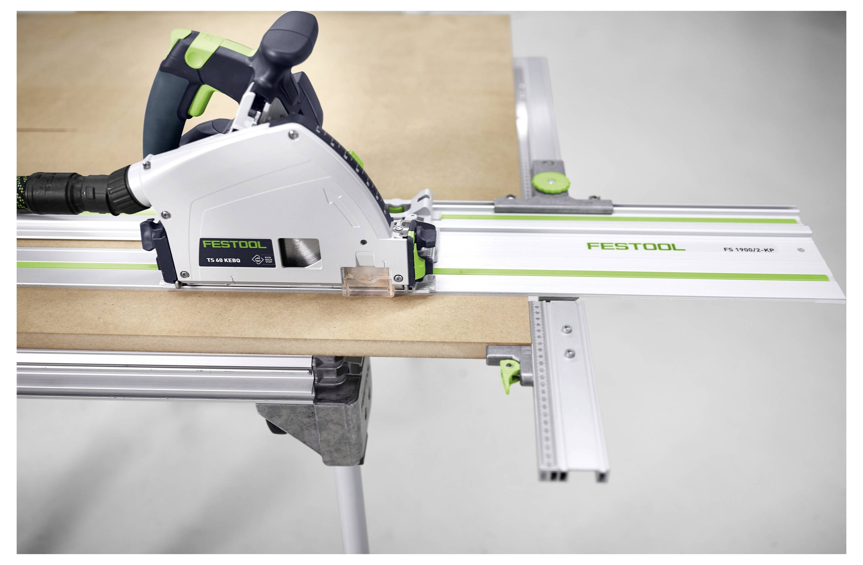 A circular saw on a guide rail cuts through a piece of wood on a workbench, illustrating precision cutting equipment use.